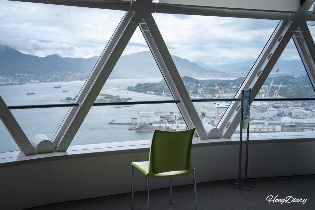 Plastic chairs on the 30th floor observation deck of Kaikyo Yume Tower facing south toward the open ocean beyond the Kanmon Strait