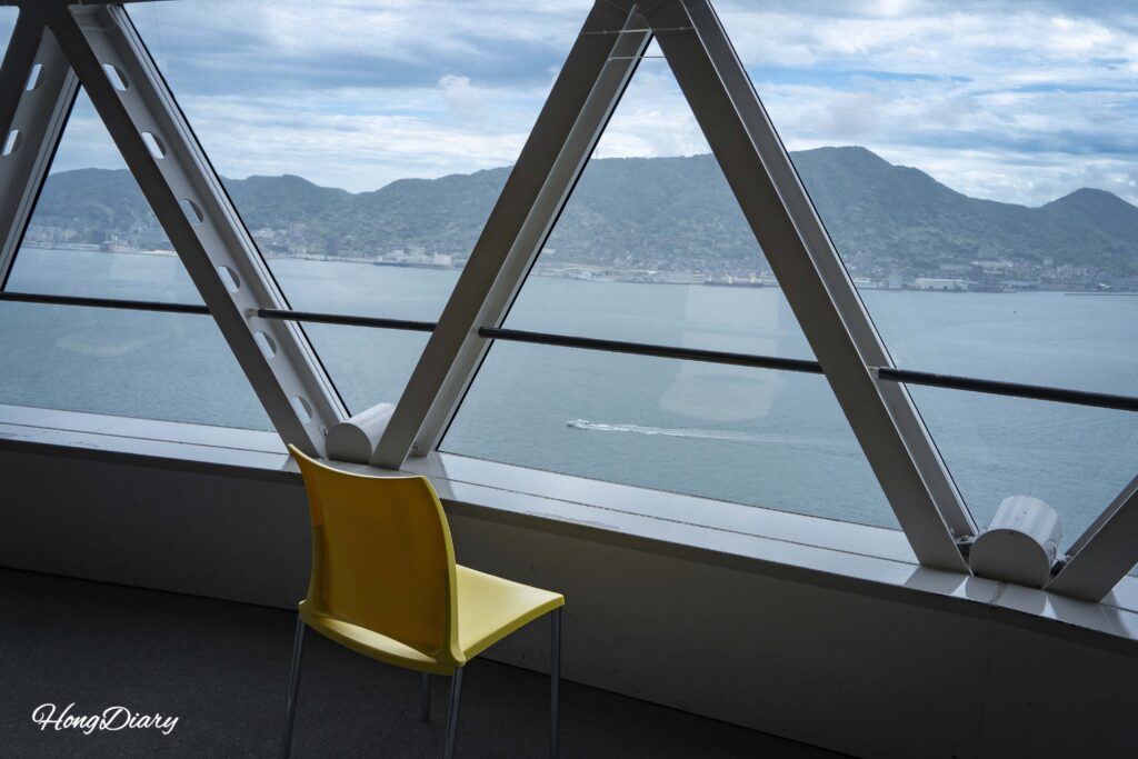 Sillas de plástico en el mirador del piso 30 de Kaikyo Yume Tower con vista hacia el sur mostrando el mar abierto más allá del Estrecho de Kanmon