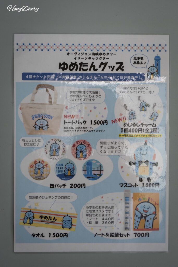 Panel en la pared de Kaikyo Yume Tower mostrando artículos del personaje Yume-tan con precios incluyendo bolsas ecológicas por 1.500 yenes y llaveros por 400 yenes