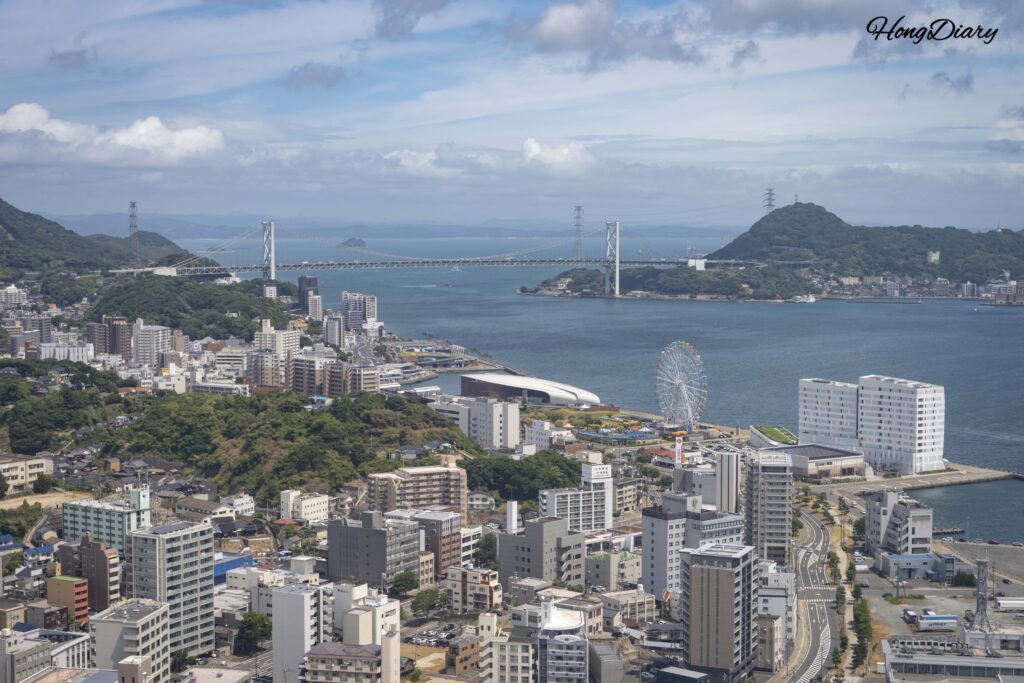 Panoramic east view from the 30th floor of Kaikyo Yume Tower showing Kanmon Bridge, Karato Market, Kaikyokan Aquarium, and the Kanmon Strait with Mojiko Retro on the Kyushu side