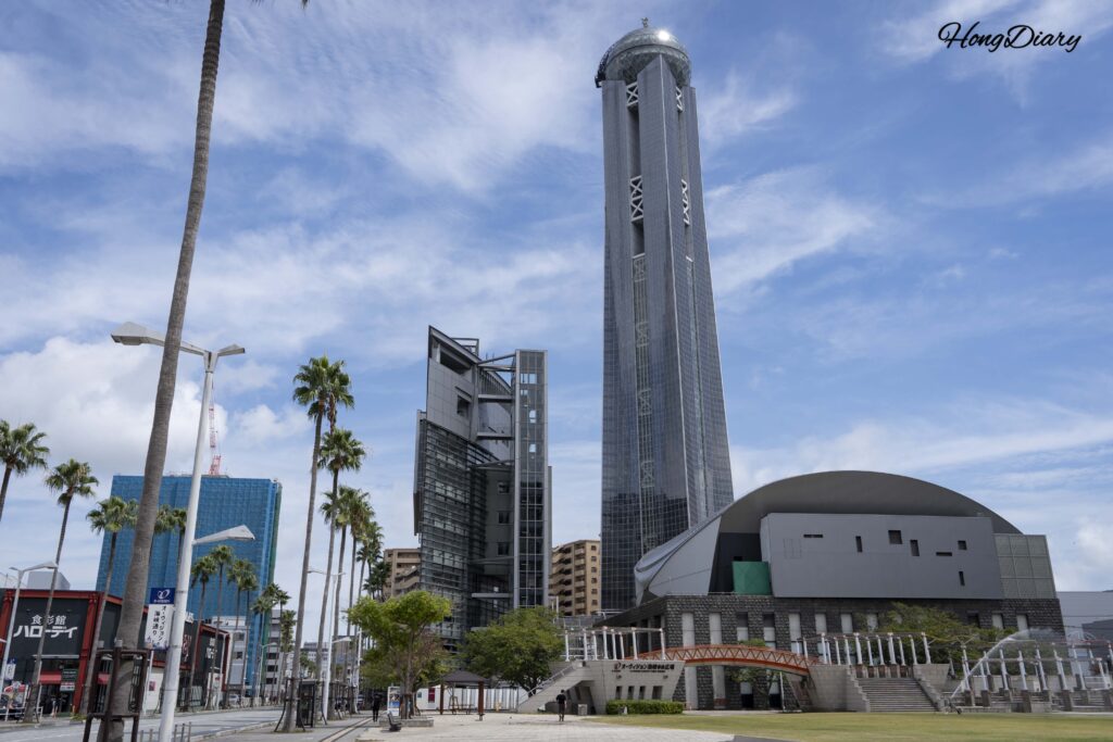 Kaikyo Yume Tower viewed from Kaikyo Yume Plaza on a clear day with the Hallo Day food market visible on the left side in Shimonoseki