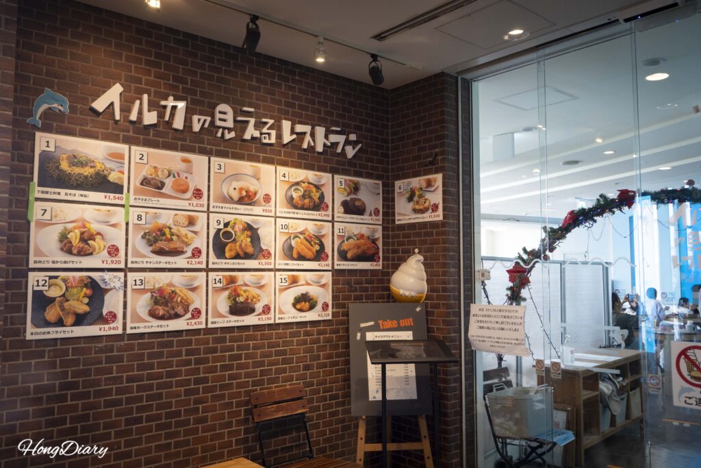 Entrance to the Kaikyokan Aquarium restaurant showing the posted menu board with prices for items including fugu tempura and children's curry
