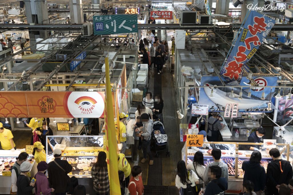 Vista desde el segundo piso del Mercado Karato mirando hacia abajo a los puestos de sushi y los visitantes en la primera planta