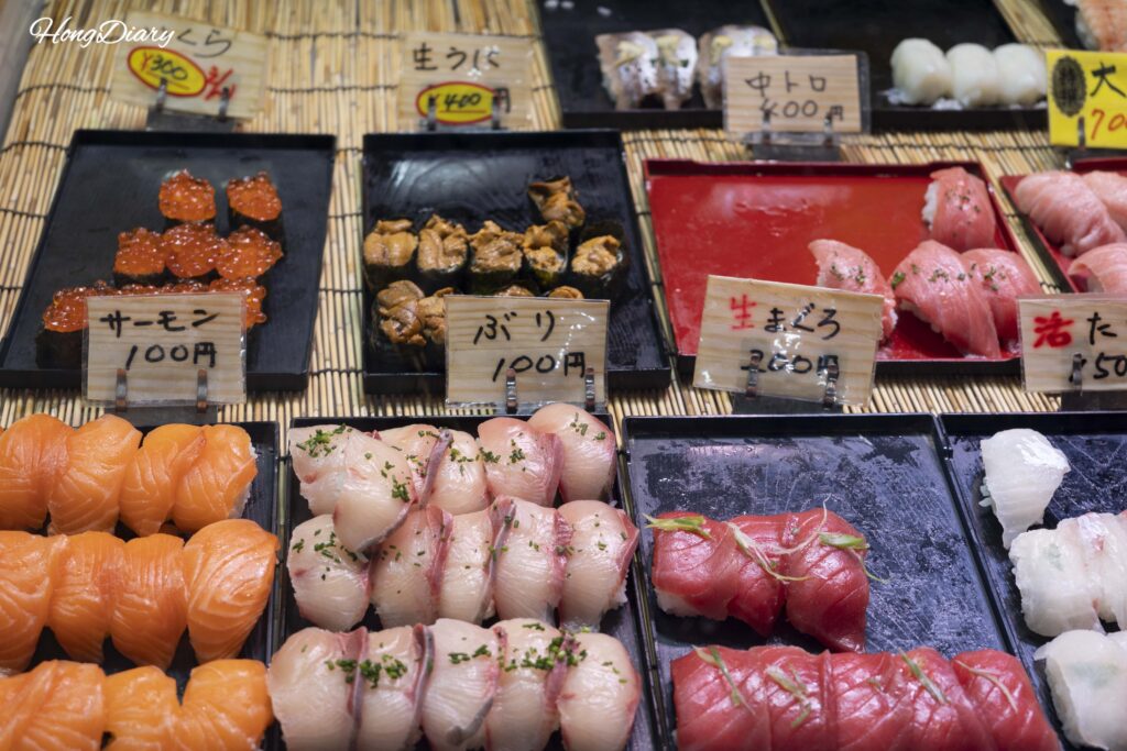 Vitrina refrigerada en un puesto del Mercado Karato con sushi variado de salmón, atún, erizo de mar e ikura, entre 100 y 700 yenes