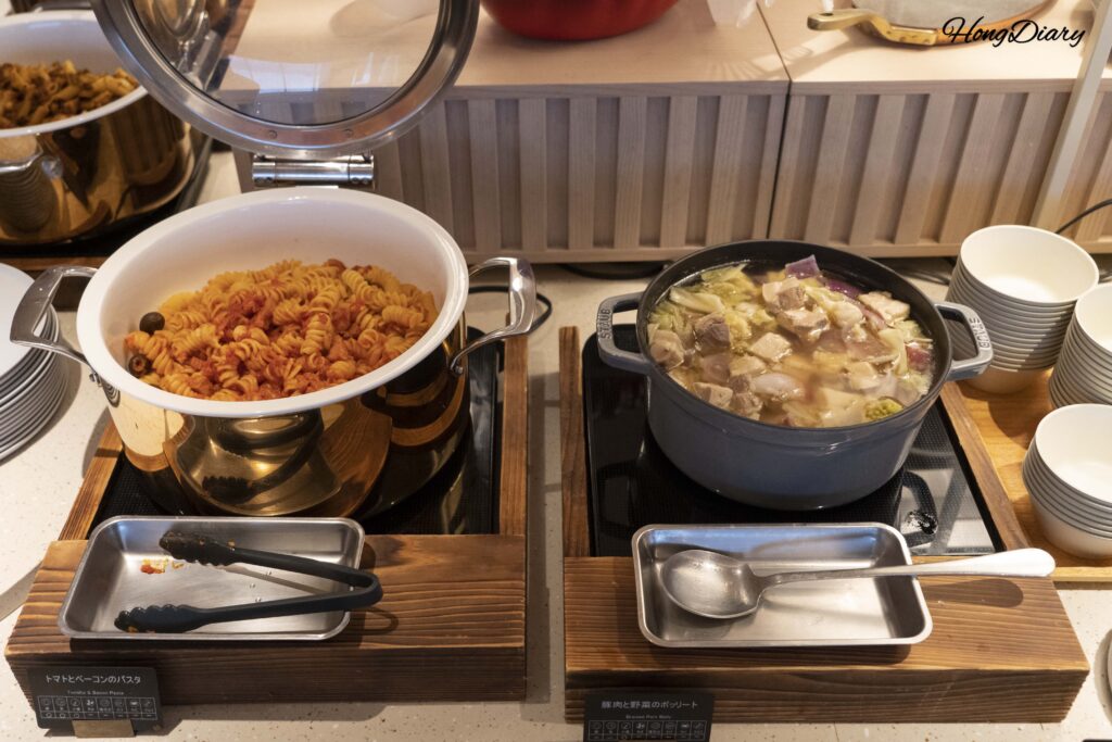 Pasta con tomate y tocino junto a sopa de cerdo y verduras en la sección de platos calientes de PUKU PUKU