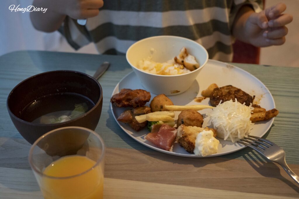 Plato servido para un niño con sopa de fugu, jugo de naranja, shumai, tortita de fugu, karaage, jamón y papas fritas en PUKU PUKU