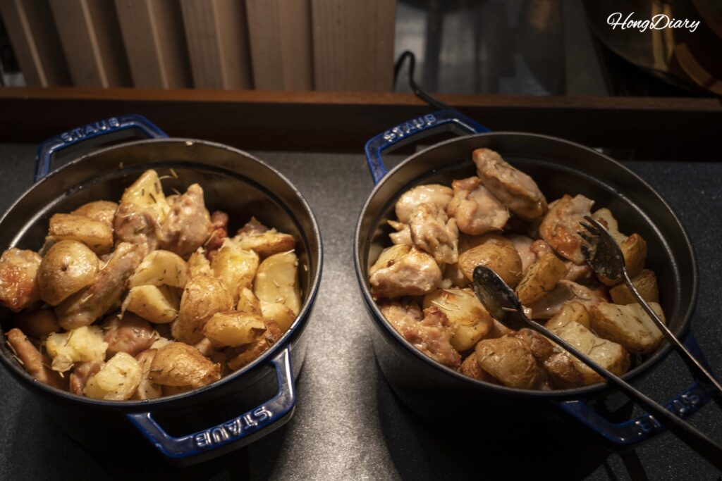 Pollo rostizado en cazuela de hierro con papas horneadas en la sección de platos calientes de PUKU PUKU