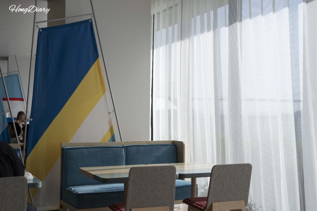 Seating area inside PUKU PUKU with ship-inspired flag installations at RISONARE Shimonoseki