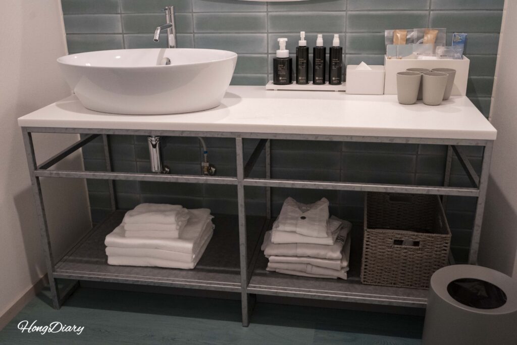 Zona seca del baño de RISONARE Shimonoseki con lavabo, toallas, pijamas y amenidades