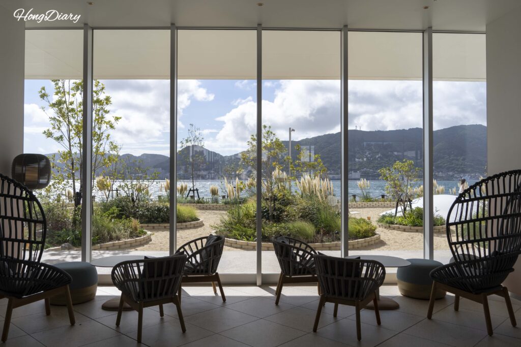 Fugu Beach sandy play area viewed from the lobby at RISONARE Shimonoseki, with the Kanmon Strait and sea visible in the background