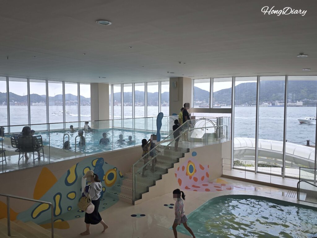 Vista general de la Fugu Pool interior de RISONARE Shimonoseki con murales de peces globo