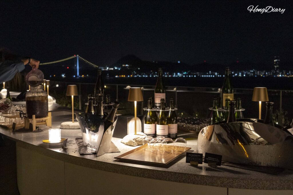 Nami Nami Terrace evening lounge at RISONARE Shimonoseki with wine and drinks on tables under warm lighting on the grass terrace