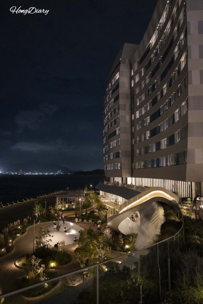 Exterior nocturno de RISONARE Shimonoseki con Fugu Beach iluminada y escalera hacia la terraza