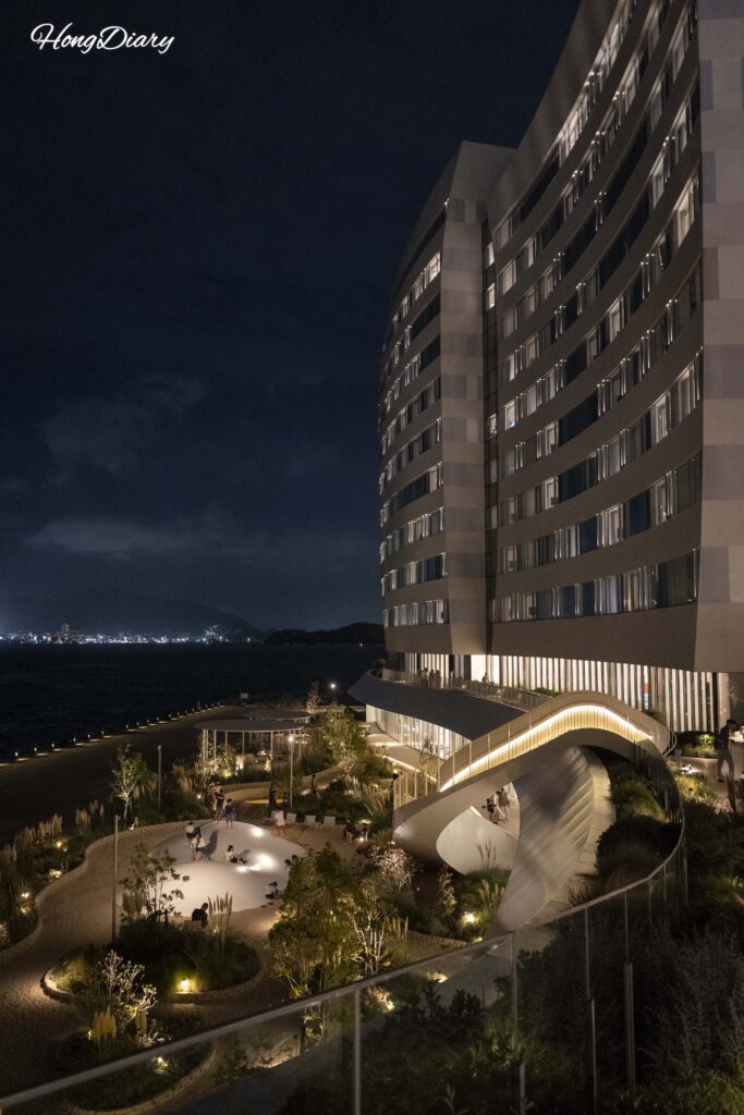RISONARE Shimonoseki lit up at night with children playing on Fugu Beach and the staircase leading up to Nami Nami Terrace