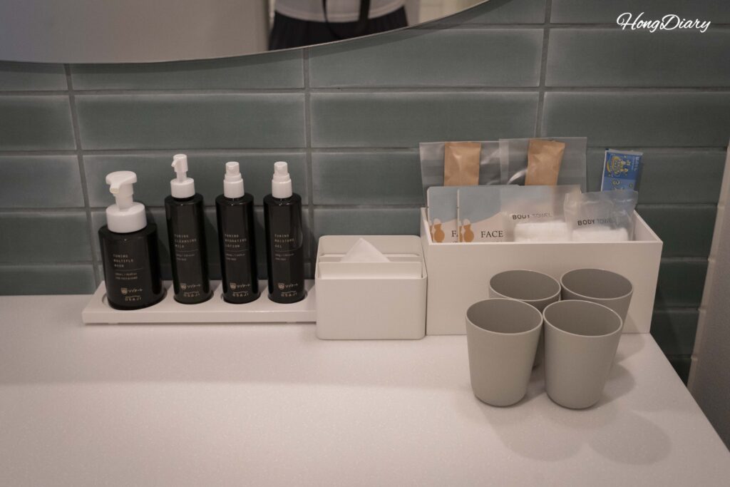 Close-up of osaji skincare amenities at RISONARE Shimonoseki including face wash, sheet masks, and basic skincare products