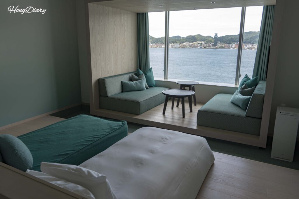 Habitación Deluxe Quad de RISONARE Shimonoseki con camas, sofá cama y ventanales con vista al Estrecho de Kanmon