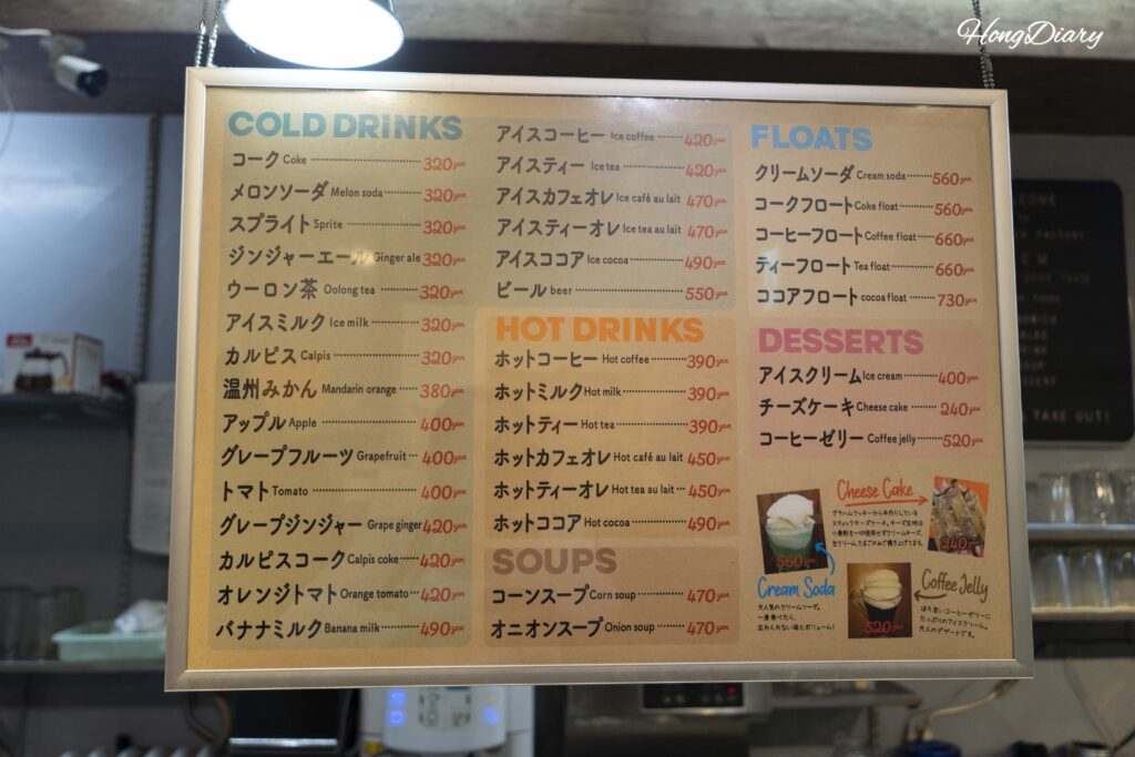 Drink and dessert menu at the register counter of Sandwich Factory OCM showing prices in Japanese yen with English labels