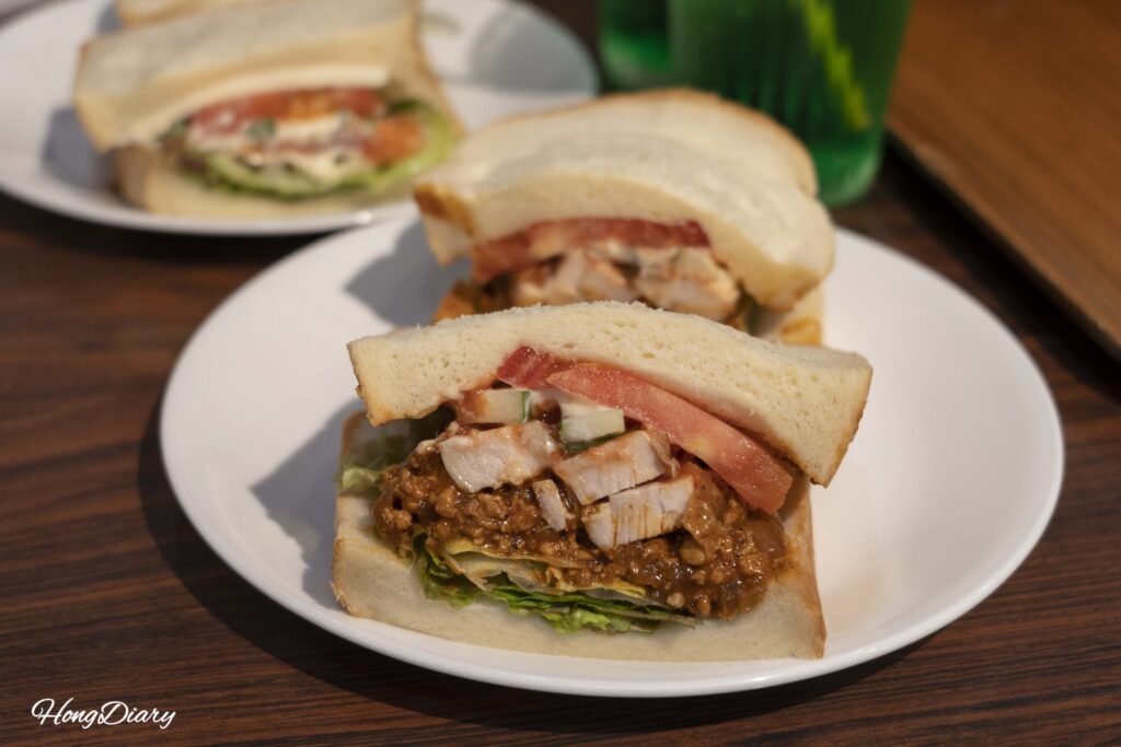 Close-up of the Original and Chicken sandwich at OCM Kitakyushu, showing thick fillings of house meat sauce and Kyushu chicken between soft white bread