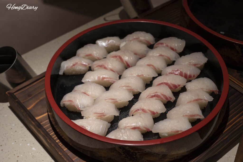 Exhibición de sushi de pescado blanco en la estación de sushi de PUKU PUKU