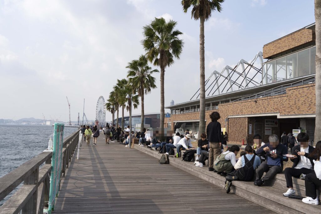 唐戸市場の海沿いデッキで大勢の来場者が寿司を広げて食事をしている風景