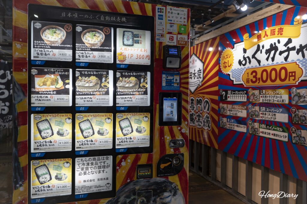 Máquina expendedora de productos de fugu operada por Yoshida Suisan en el Mercado Karato, con artículos de 300 a 2.000 yenes